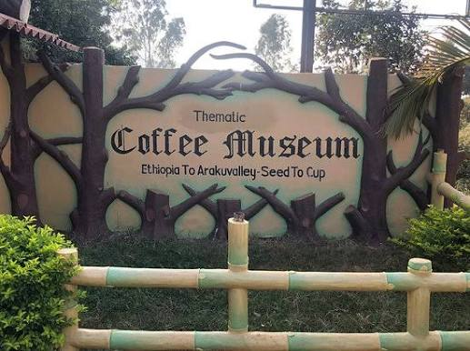 Thematic Coffee Museum sign in Araku, framed by a painted tree mural